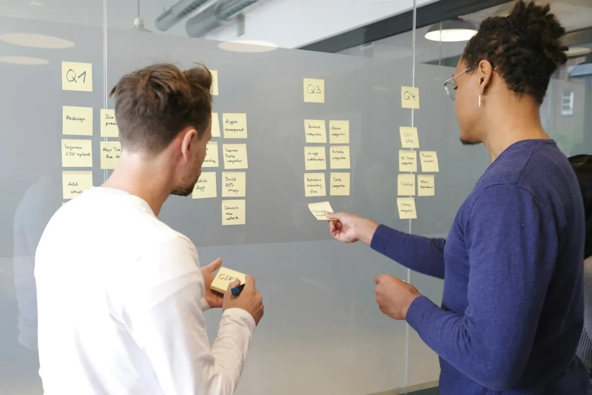 Two people planning with sticky notes on a glass wall